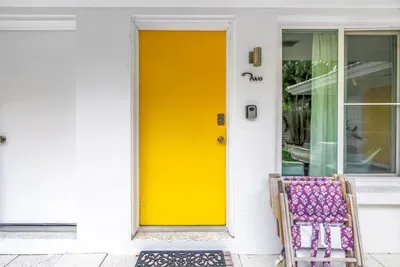 Sunny yellow entry door with charming outdoor seating and inviting curb appeal