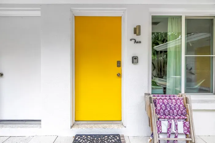 Sunny yellow entry door with charming outdoor seating and inviting curb appeal