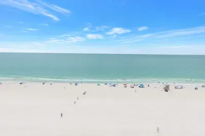 Wide white-sand beach with calm turquoise water and panoramic ocean views