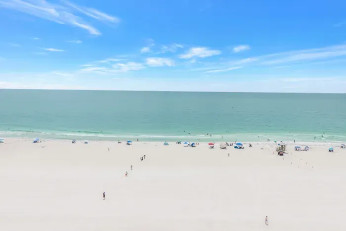 Wide white-sand beach with calm turquoise water and panoramic ocean views