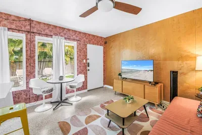 Bright tropical lounge with TV, dining nook, and sunny garden views