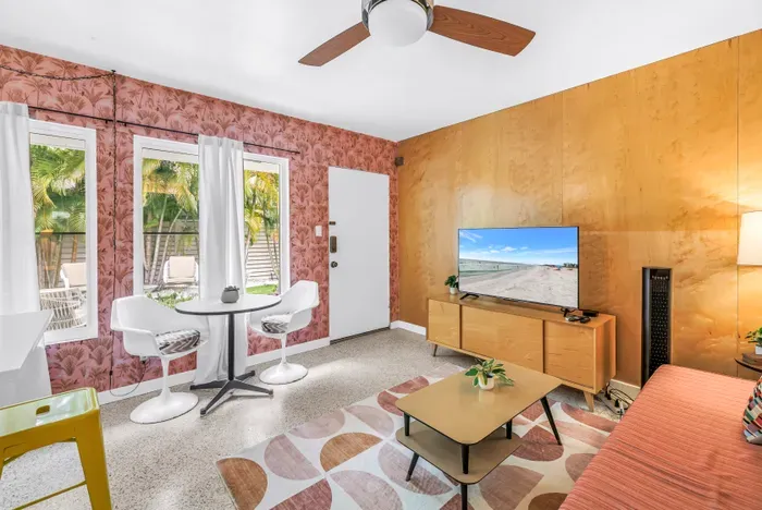 Bright tropical lounge with TV, dining nook, and sunny garden views
