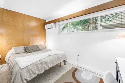 Bright, cozy bedroom with warm wood accents and leafy window views
