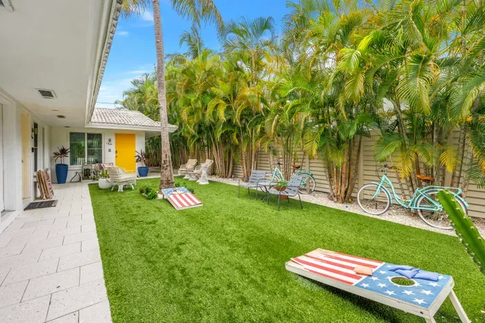 Private tropical courtyard with lawn games, seating, and lush palm views