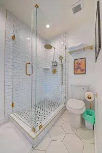 Shared bathroom off of the living room has a luxury rain shower and single sink vanity.