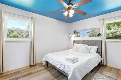 Bright bedroom with plush bed, natural light, and a stylish blue ceiling
