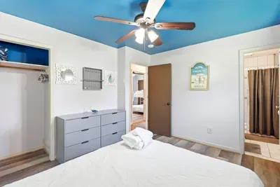 Bright coastal bedroom with bold blue ceiling and easy bathroom access