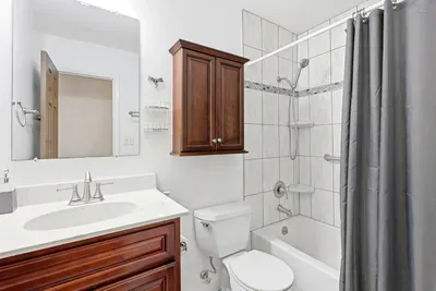 Bright updated bathroom with tiled tub-shower and elegant wood vanity