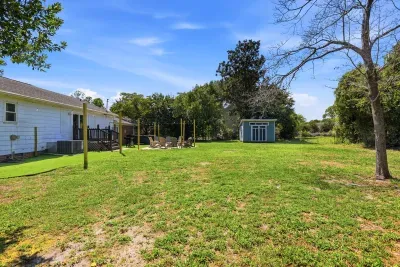 Spacious backyard with fire pit, deck seating, and open green space