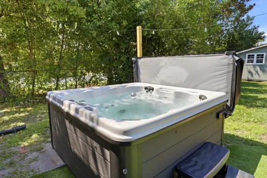 Private backyard hot tub with string lights and a peaceful garden setting