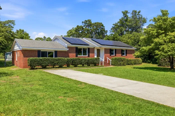 Charming brick home with solar panels, spacious lawn, and easy parking