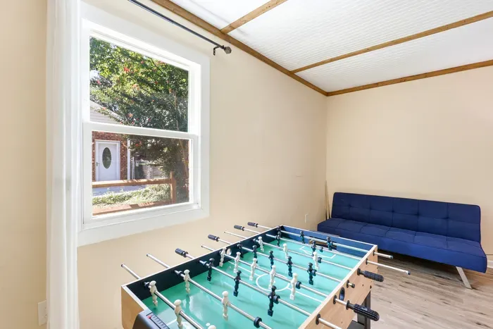 Sunny game room with foosball table and cozy blue futon seating