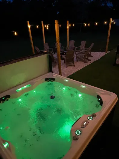 Private hot tub and cozy fire pit seating under glowing string lights