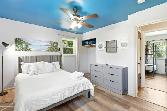 Bright, stylish bedroom with blue ceiling, comfy bed, and natural light