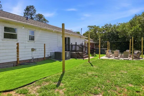 Spacious backyard with deck, turf lawn, and cozy fire pit seating area