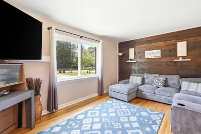 Cozy living room with sectional, wood accent wall, and sunny picture window