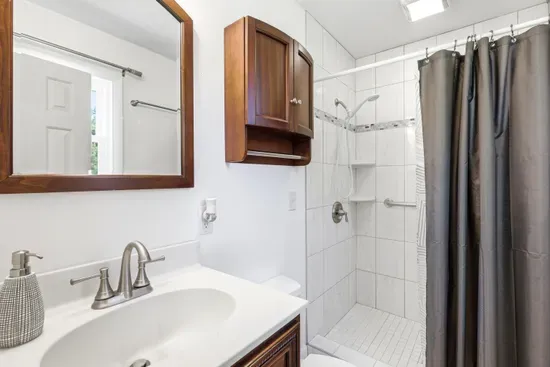 Bright bathroom with walk-in tiled shower and warm wood accents