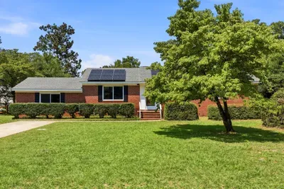 Charming brick home with spacious lawn, shade trees, and solar panels