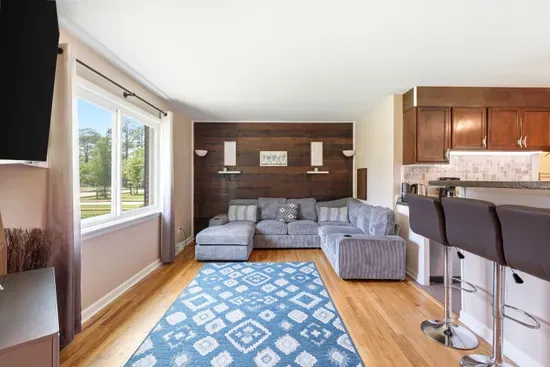 Bright living room with cozy sectional, wood accent wall, and breakfast bar