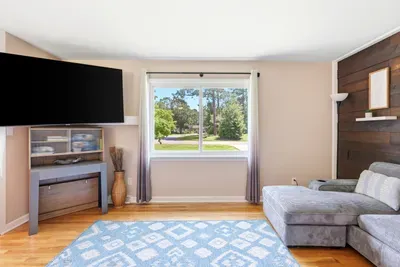 Bright living room with large window, sectional chaise, and mounted TV