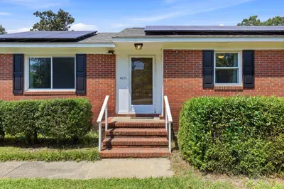 Charming brick home entry with solar panels and manicured curb appeal