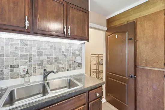 Warm kitchen with double sink, wood cabinets, and stylish tile backsplash