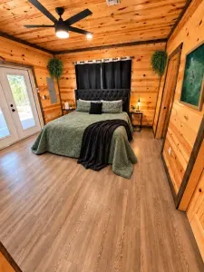 Cozy wood-lined bedroom with plush bed, blackout curtains & French doors