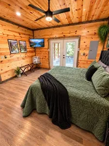 Cozy wood-lined bedroom with French doors and serene cabin charm