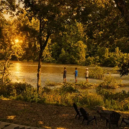 Golden-hour riverside retreat with fire pit, seating, and tranquil views