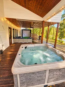 Covered deck with hot tub, lounge seating, and outdoor movie screen