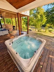 Private hot tub on a covered deck with peaceful river and woodland views