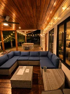Covered deck with cozy sectional, string lights, and private hot tub
