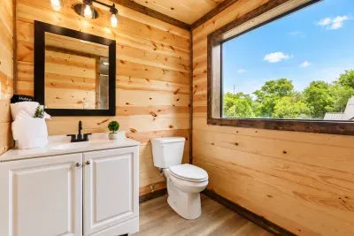 Bright rustic bathroom with large window and peaceful treetop views