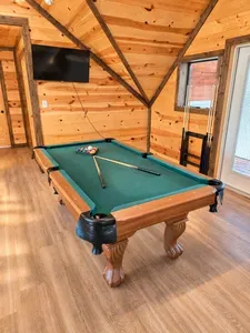Cozy cabin game room with pool table, TV, and warm wood interiors