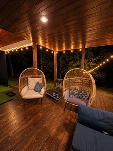 Cozy covered deck with string lights and woodland views
