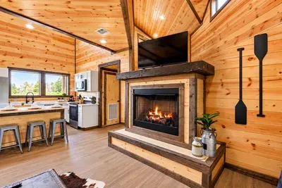 Cozy cabin great room with fireplace, TV, and bright open kitchen