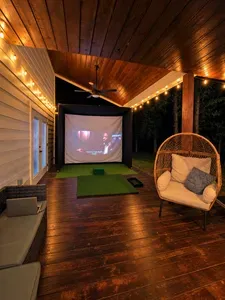 Cozy covered deck with string lights, projector screen, and lounge seating