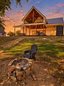 Sunset-lit cabin retreat with fire pit, string lights, and spacious porch