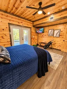 Rustic wood-clad bedroom with TV, French doors, and cozy lodge charm