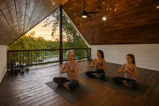 Serene covered yoga deck with river views and warm ambient lighting