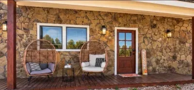 Inviting stone-front porch with cozy seating and rustic charm