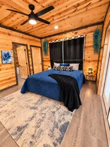 Cozy cabin-style bedroom with luxe blue bedding and warm wood interiors