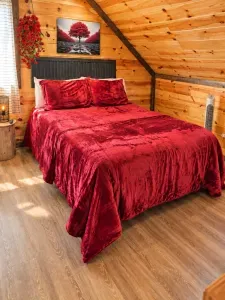 Cozy cabin bedroom with plush red bedding and warm rustic charm