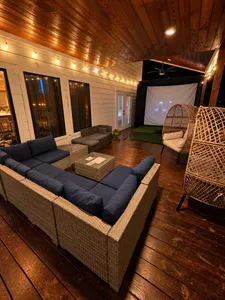 Covered outdoor lounge with projector screen, string lights & cozy seating