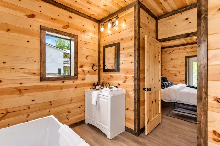 Rustic wood-paneled bath with soaking tub and cozy bedroom access