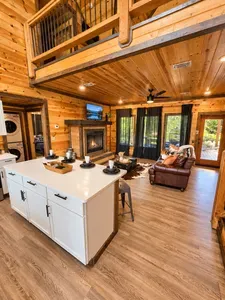 Rustic log cabin great room with fireplace, loft, and bright open layout