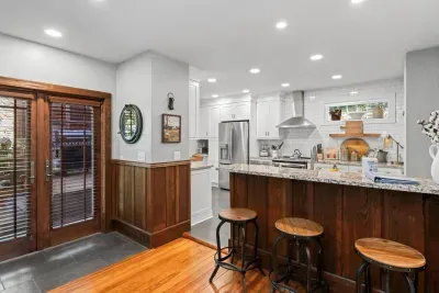 The recently renovated, open kitchen features three bar stools and new appliances.