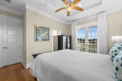 Bright coastal bedroom with French doors opening to a private balcony