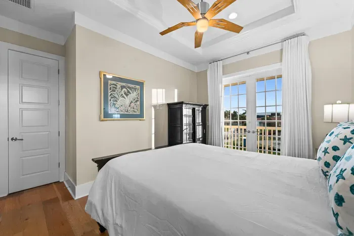 Bright coastal bedroom with French doors opening to a private balcony