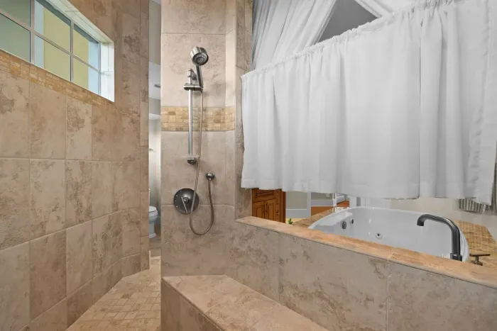 Spa-like bath with tiled walk-in shower, soaking tub, and elegant finishes